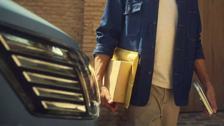 Renault Geschaeftskunde_Arm mit Unterlagen Scheinwerfer eines Autos